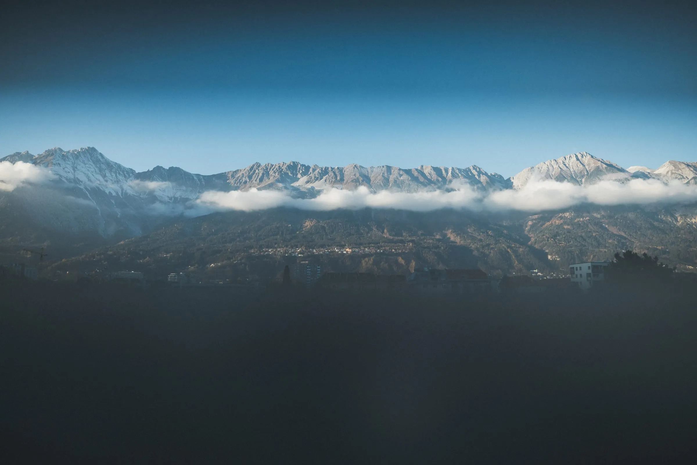 Blick über Innsbruck auf die Nordkette, an deren Hängen Wolken liegen